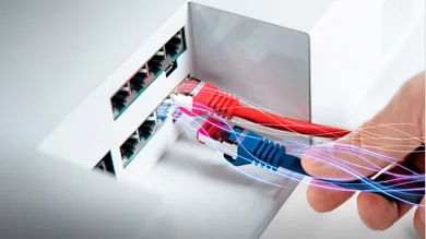 Das Bild zeigt die Hand einer Person, die ein blaues Kabel in den passenden Anschluss des SmartDrivers des ESYLUX Light Control System steckt. Ein rotes Kabel ist bereits eingesteckt. Der SmartDriver ist weiß.